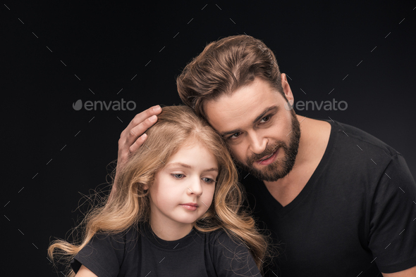 adorable little daughter and father hugging her isolated on black