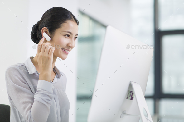 Young businesswoman with Bluetooth headset working in office