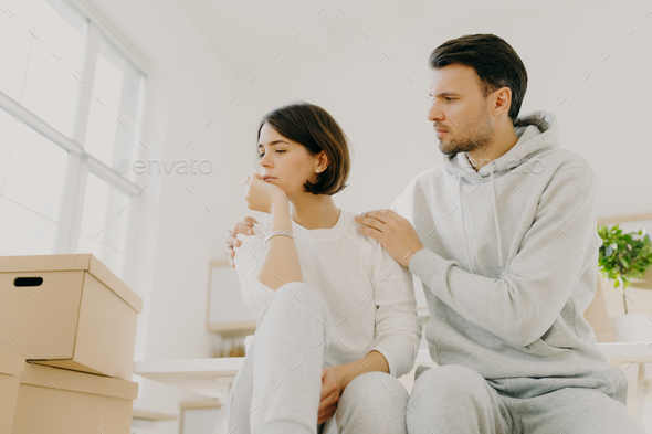Sad woman complains about problems, man calms, embraces wife, tired after bringing many boxes