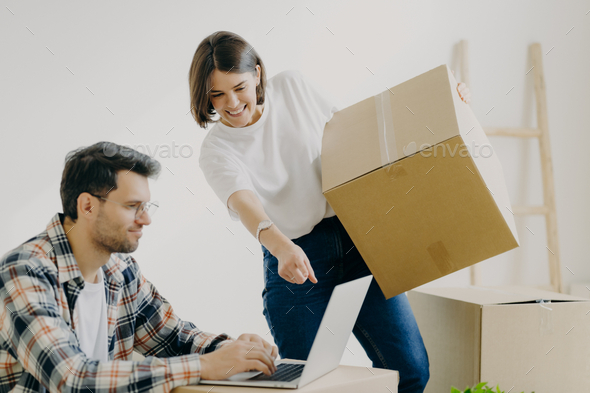 Family look attentively at laptop computer, search good moving company, carry personal belongings