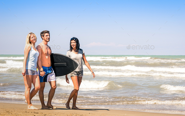 Group of young happy people on vacations at the beach holding a surf table