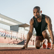 Low angle view of young man athlete in starting position for running on  sports track Stock Photo