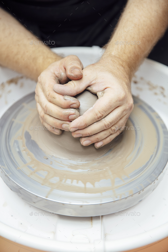 View at an artist makes clay pottery on a spin wheel