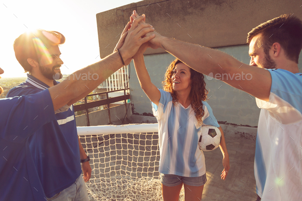 Friends doing high five before playing football match