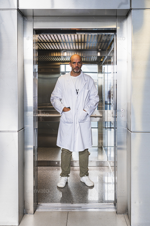 Scientist dressed in a white coat inside an elevator.