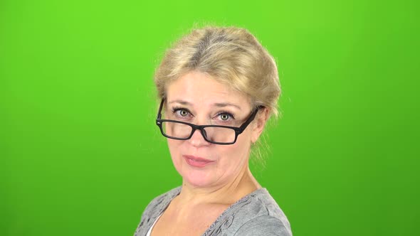 Woman Smiles and Drops Her Glasses at the Eyes. Green Screen alt