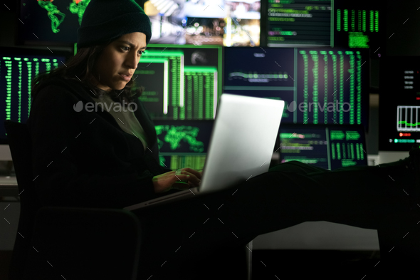 Latina female hacker using laptop to organize malware attack on global scale.