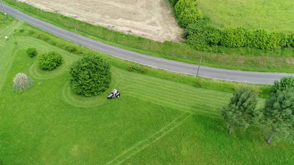 Riding lawn mower in action seen from the sky alt
