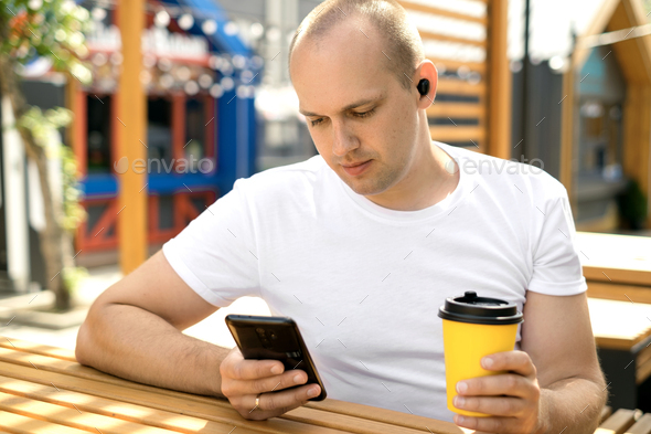 Man listening to music with wireless earbuds with a cup of coffee