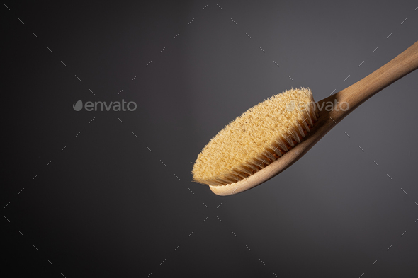 wooden brush for body dry massage anti cellulite peeling body care. on dark background Close-up