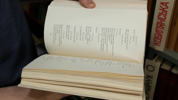 Student Leafing Through A Book In The Library