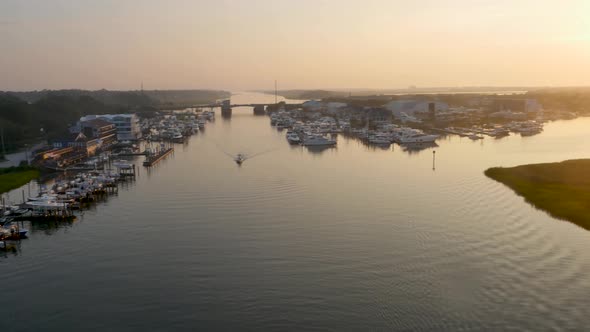 4k view of small beach town at sunrise over the water way revealing boats and green marsh early in t alt