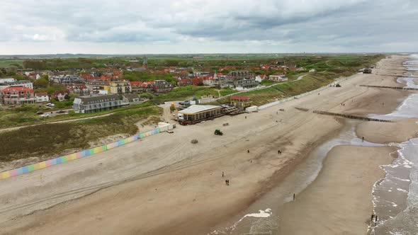 Long aerial shot of a beach and the North Sea at low tide outside a small, picturesque Dutch town on alt
