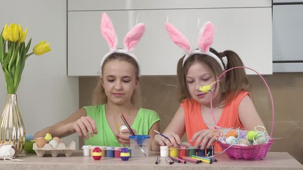 Two Sister Girls are Decorating Easter Eggs in the Kitchen