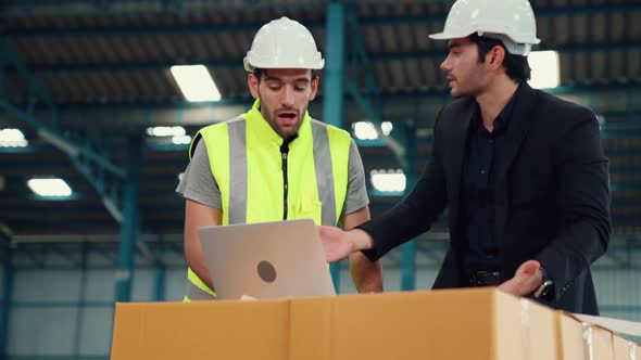Two Factory Workers Working and Discussing Manufacturing Plan in the Factory alt