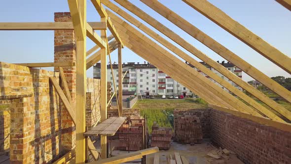 Aerial view of unfinished brick house with wooden roof structure under construction. alt