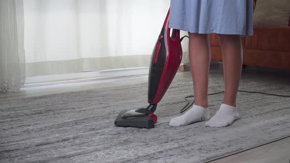 A Woman Vacuums a Carpet