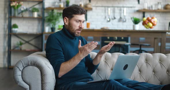 Side View Bearded Man Entrepreneur Talking Video Call at Home Sitting on the Sofa at Home alt