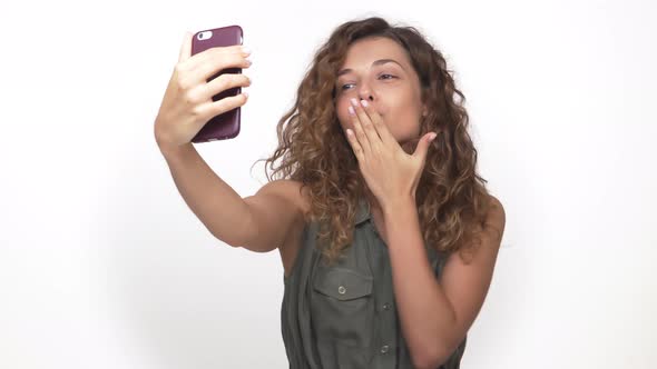 Portrait of Attractive Playful Lady Making Selfie Photo on Mobile Phone Doing Air Kiss Isolated on alt