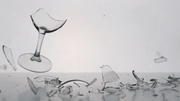 A clear winegalss falls and breaks on a white table
