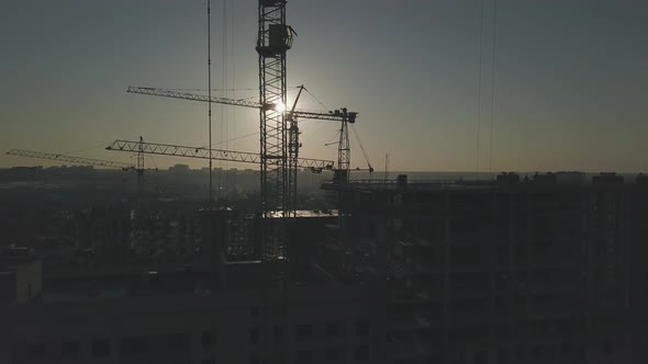 Construction Site at Sunset. Silhouette of a Construction Crane Near the Building