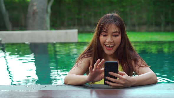 happy woman using smartphone in swimming pool