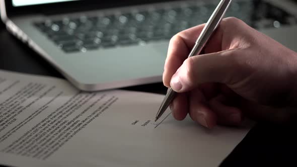 Close Up Shot of the Man's Hand Who Leaves His Signature on Business Document. alt