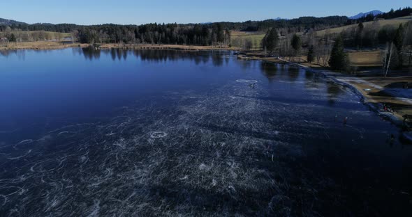 Aerial view of frozen lake with people ice skating alt