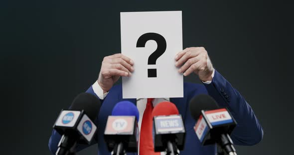 Politician hiding his face with a sign during a press interview