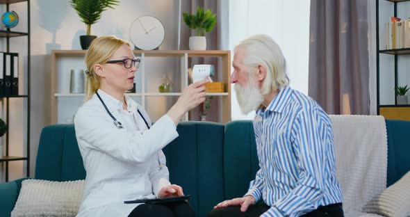 Doctor Checking Body Temperature of Mature Bearded Man Using Non-Contact Infrared Thermometer alt