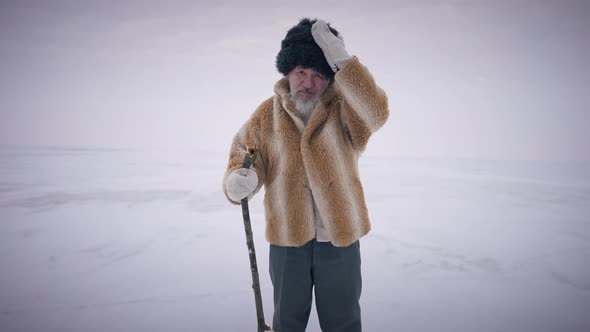 Portrait of Confident Indigenous Old Bearded Man Standing on Icy Frozen Arctic Ocean Looking at alt
