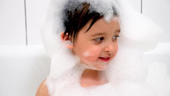 Three Year Old Boy with Big Eyes Bathes in a White Bathroom with Black Stripes alt