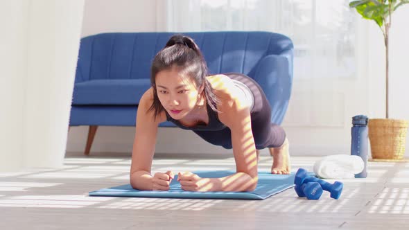 Athletic Asian woman practice yoga Plank pose to meditation at home Feeling so comfortable and relax alt