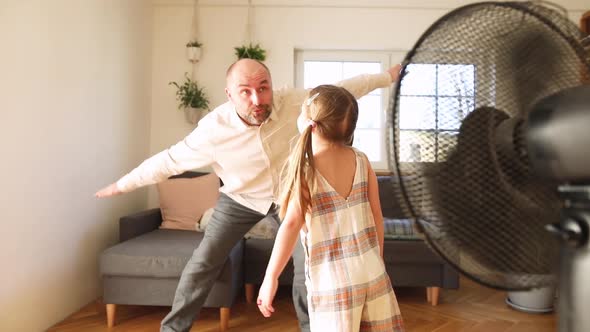 Father playing with his daughter pretending to fly at home alt