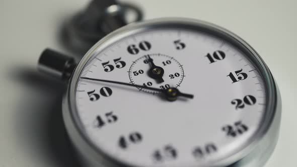 Macro shot of a classic metallic retro mechanical analog stopwatch against a white background alt