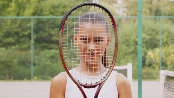 Young beautiful sportswoman with tennis racket at tennis net on tennis court. Sports Fashion