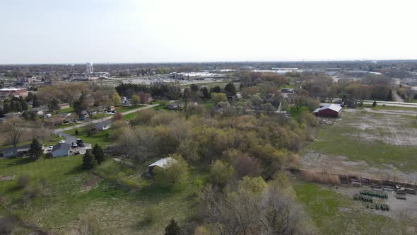 Aerial view at edge of midwest town with blue sky, open farm field and residential homes.