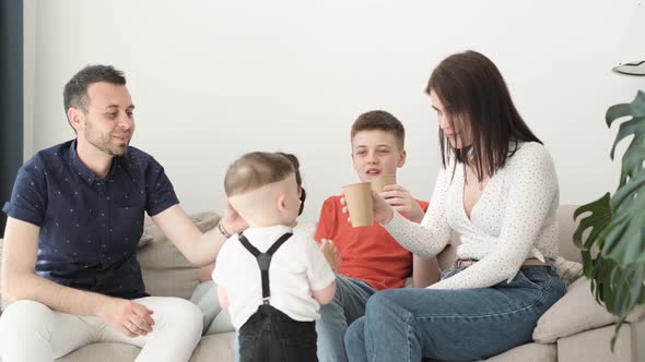 A Happy Friendly Family with Three Children is Drinking Tea in the Living Room alt