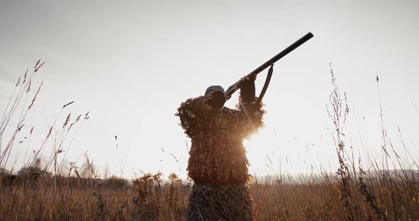 Hunter Aims the Target With Rifle in the Field at Foggy Morning or Sunny Autumn Evening alt