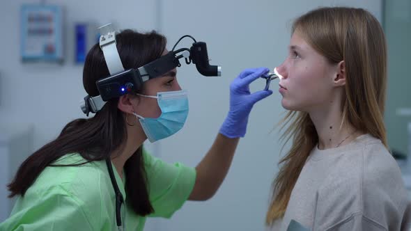 Side View Focused Caucasian Doctor Checking Nose of Teenage Patient in Hospital Indoors alt