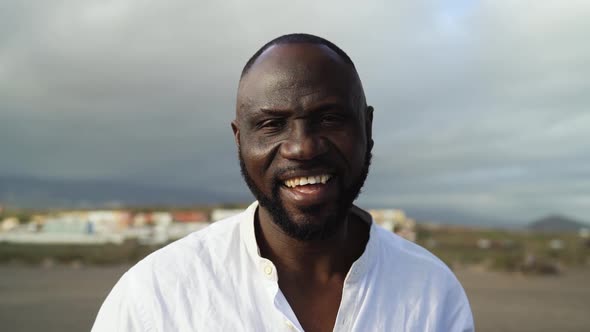 Happy African man smiling in camera on the beach during summer vacation