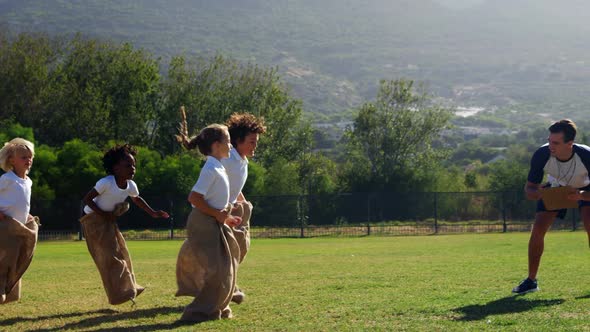 Children playing a sack race in park alt