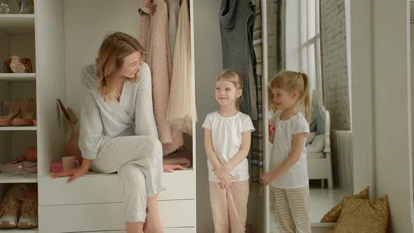 Mom Sits on the Closet and Looks at the Camera with Her Daughters