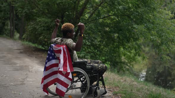 Soldier in Wheelchair Gesturing Strength in Slow Motion Admiring Lake in Forest alt