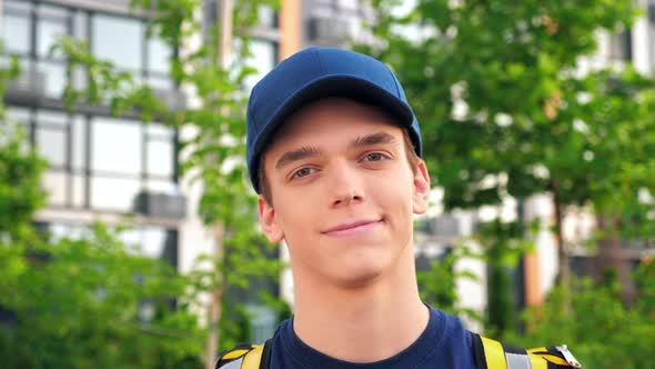 Close Up Smiling Young Man Courier Delivery with Thermal Backpack Looking Camera alt