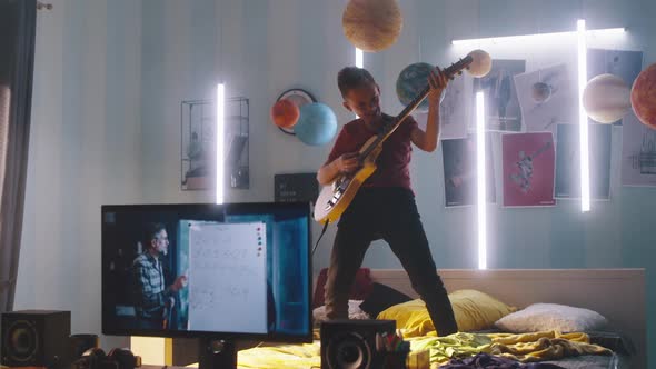 Teenager Playing Electric Guitar During Online Lesson alt