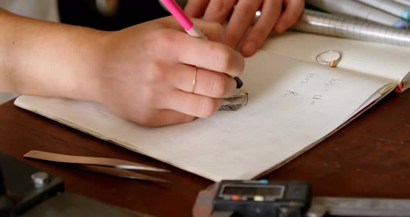 Female jewelry designer drawing sketch on register 4k alt