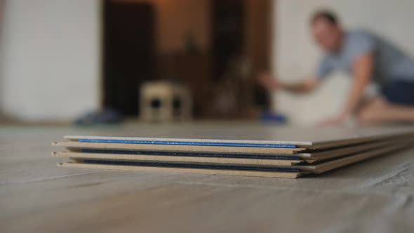 Closeup a Stack of Laminate is Lying on the Floor in the Apartment the Master Takes a Bar of