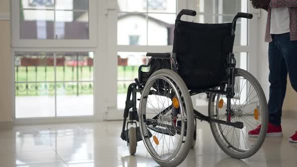 Wheelchair Standing in Living Room with Unrecognizable African American Man and Girl Entering alt