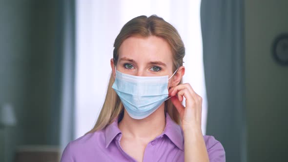 Young woman taking off the medical blue mask alt